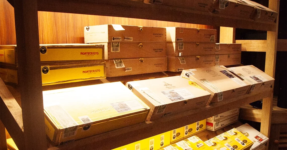 Cajas de habanos Montecristo originales con sello de garantía en la estantería de The Cigar Humidor